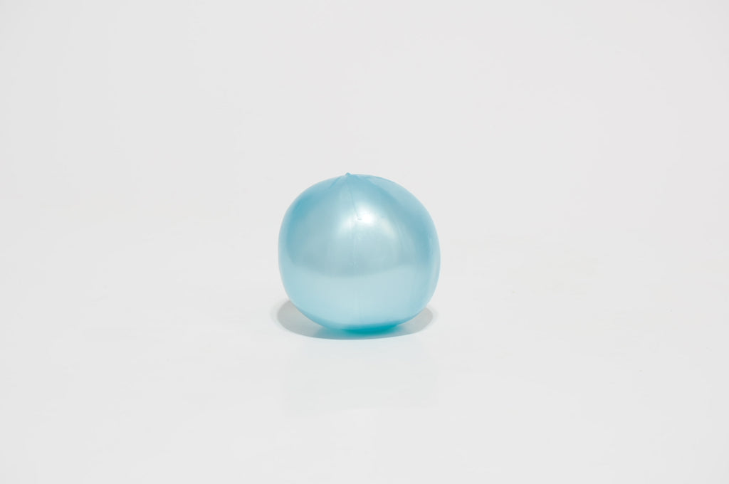 Single translucent light blue oil squishy ball with a glossy surface, photographed against a white background.