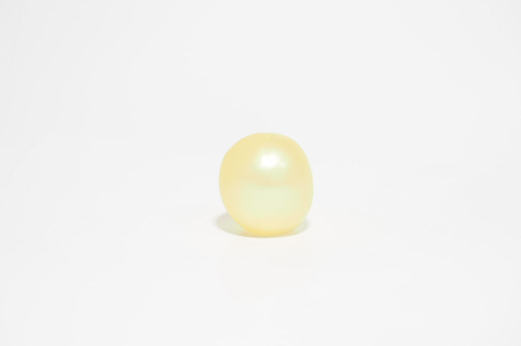 Single translucent yellow oil squishy ball with a smooth, glossy surface, photographed against a white background.