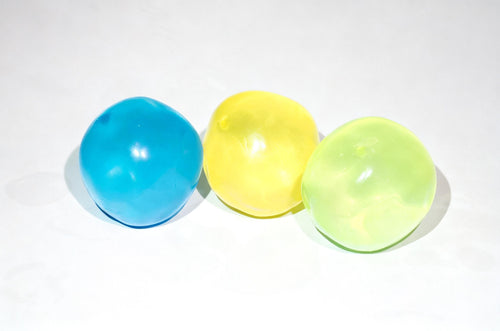 Three translucent Oil Squish balls in blue, yellow, and light green, arranged in a row on a white background.