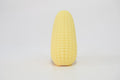 Yellow corn-shaped crunchy squishy toy standing upright on a white surface, showing its long, rounded shape and textured corn-like exterior.