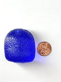 Deep blue-purple translucent gumdrop squishy with a pebbled surface, shown beside a penny.